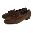 A dark brown suede tassel loafer with a Vegano Moka leather trim, displaying an almond-shaped toe and a fine ridged rubber sole.