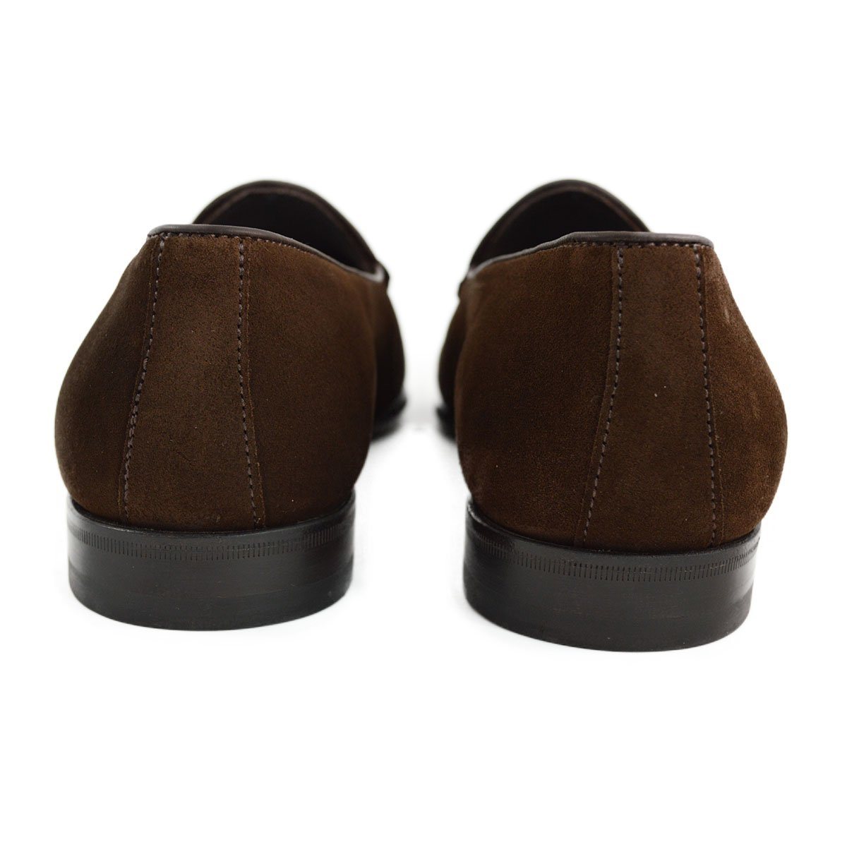 A dark brown suede tassel loafer with a Vegano Moka leather trim, displaying an almond-shaped toe and a fine ridged rubber sole.