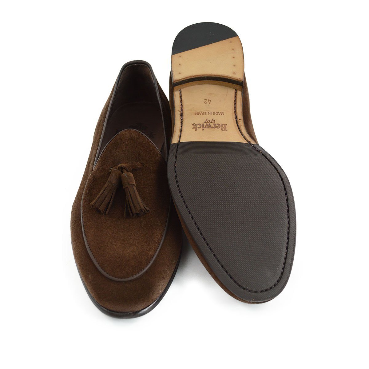 A dark brown suede tassel loafer with a Vegano Moka leather trim, displaying an almond-shaped toe and a fine ridged rubber sole.