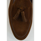 A dark brown suede tassel loafer with a Vegano Moka leather trim, displaying an almond-shaped toe and a fine ridged rubber sole.