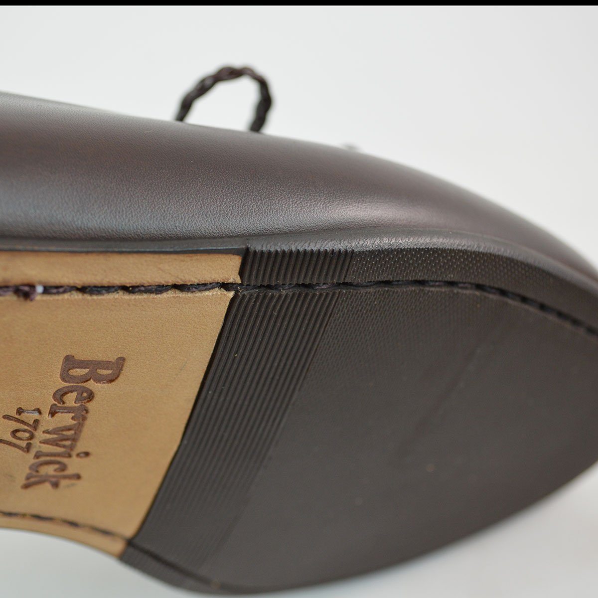 A Berwick 1 707 dark brown leather Belgian loafer with a braided leather bow tie and tassel adornment.