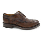 A Berwick 1707 brown brogue derby shoe with a round toe shape and lace-up closure. It features a grainy texture and brogue detailing & Dainite soles