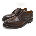 A Berwick 1707 brown brogue derby shoe with a round toe shape and lace-up closure. It features a grainy texture and brogue detailing & Dainite soles