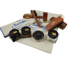 An assortment of shoe care products from Saphir Medaille D'Or including polishing cloths, brushes, cream polishes in black and medium brown, a shoe bag and a neutral wax polish.