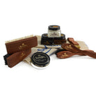 An assortment of shoe care products from Saphir Medaille D'Or including polishing cloths, brushes, cream polishes in black and medium brown, a shoe bag and a neutral wax polish.