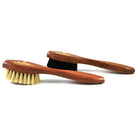 A long-handled spatula-shaped shoe polish applicator brush with black & neutral bristles and a wooden handle.