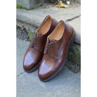 A dark brown, grainy-textured leather derby shoe with a round toe and classic lace-up closure & Dainite soles