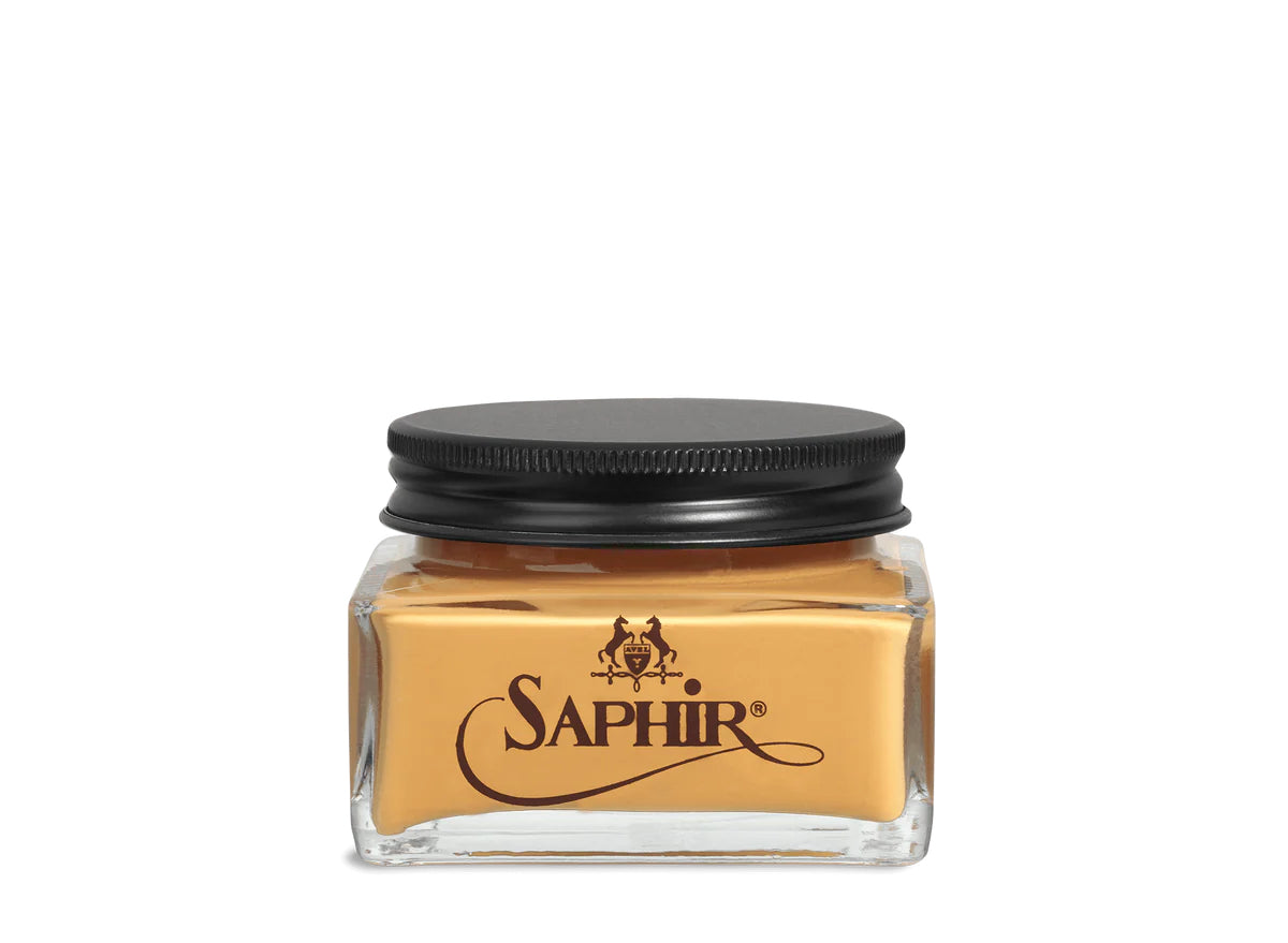 A glass jar with a black lid labeled 'SAPHIR' containing cream shoe polish.