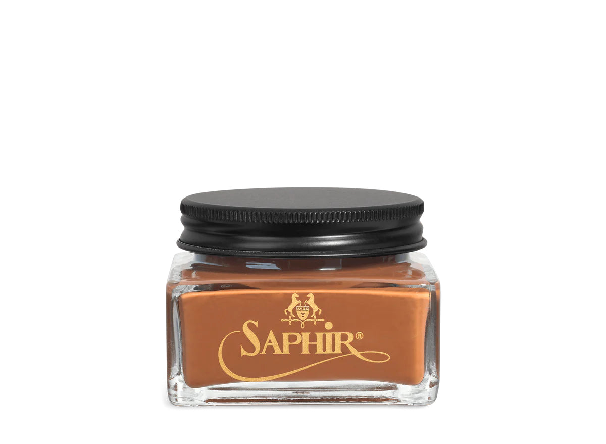 A glass jar with a black lid labeled 'SAPHIR' containing cream shoe polish.