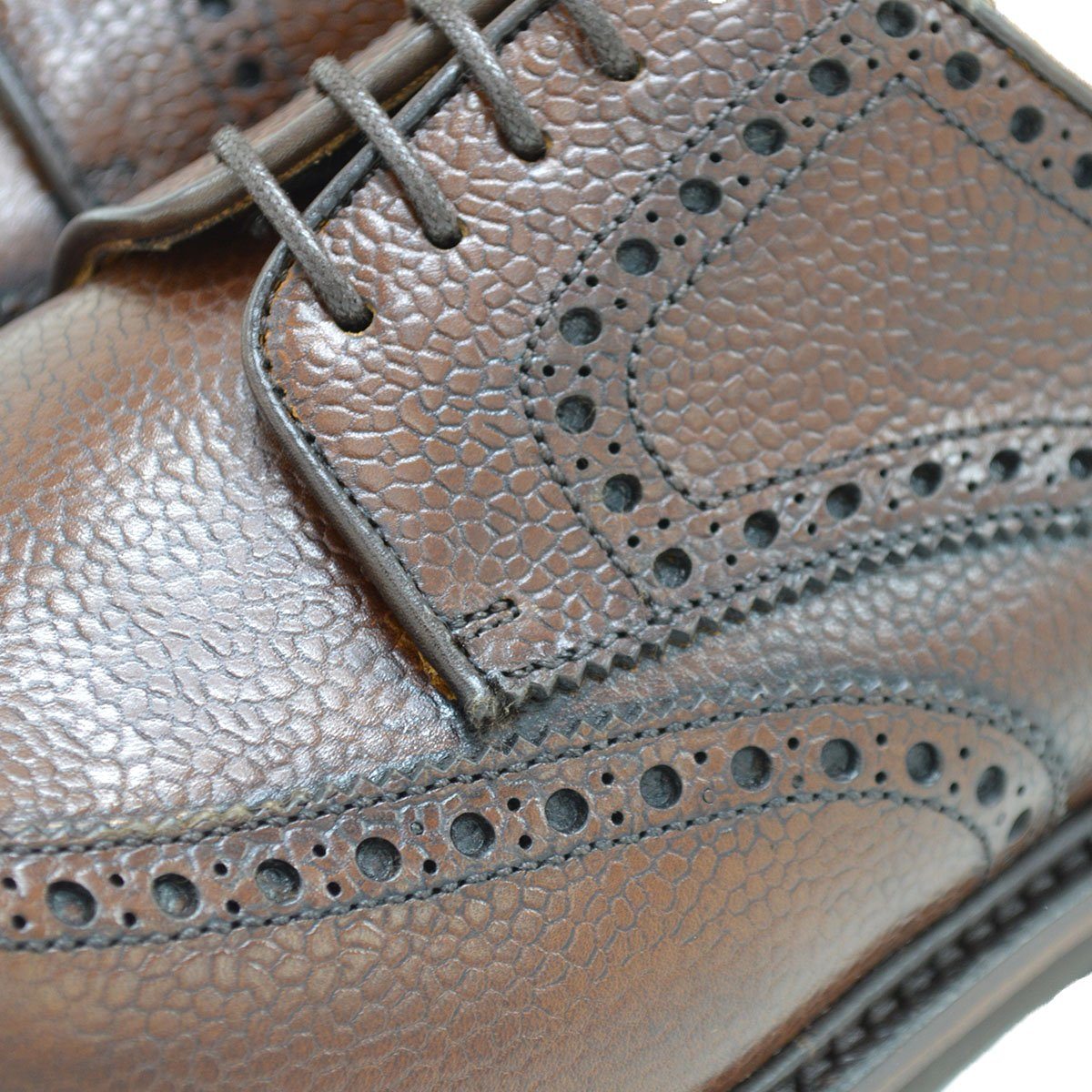 A Berwick 1707 brown brogue derby shoe with a round toe shape and lace-up closure. It features a grainy texture and brogue detailing & Dainite soles