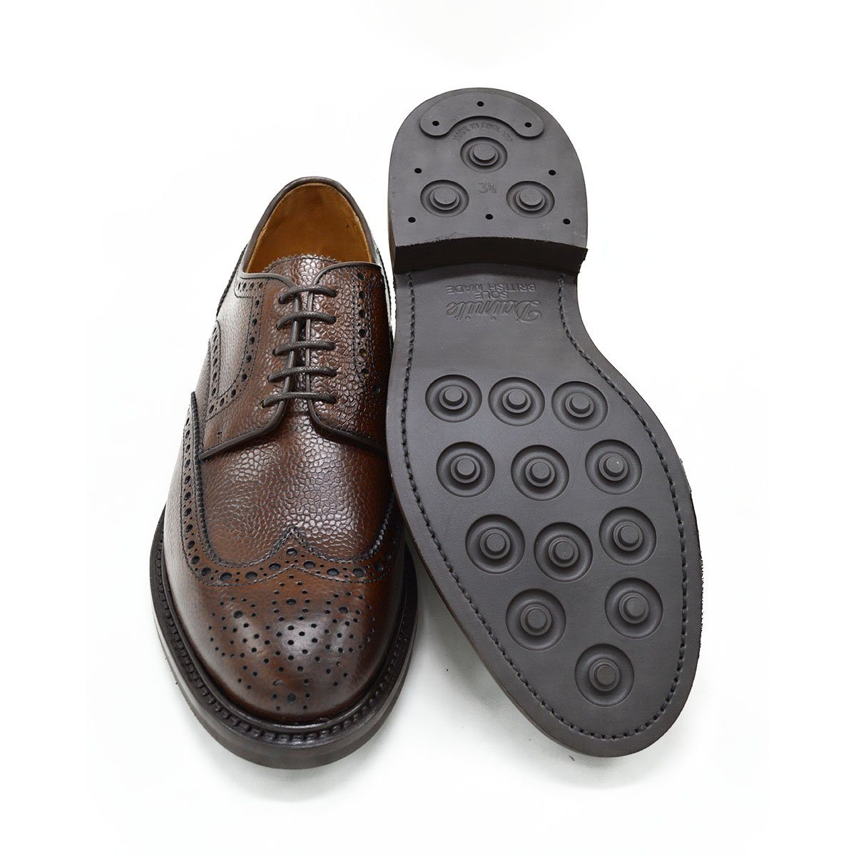 A Berwick 1707 brown brogue derby shoe with a round toe shape and lace-up closure. It features a grainy texture and brogue detailing & Dainite soles