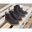 A dark brown Trickers Bernwood service boot made of Hydro Nubuck with a Dainite sole, featuring brass eyelets and a cream Barbour welt.